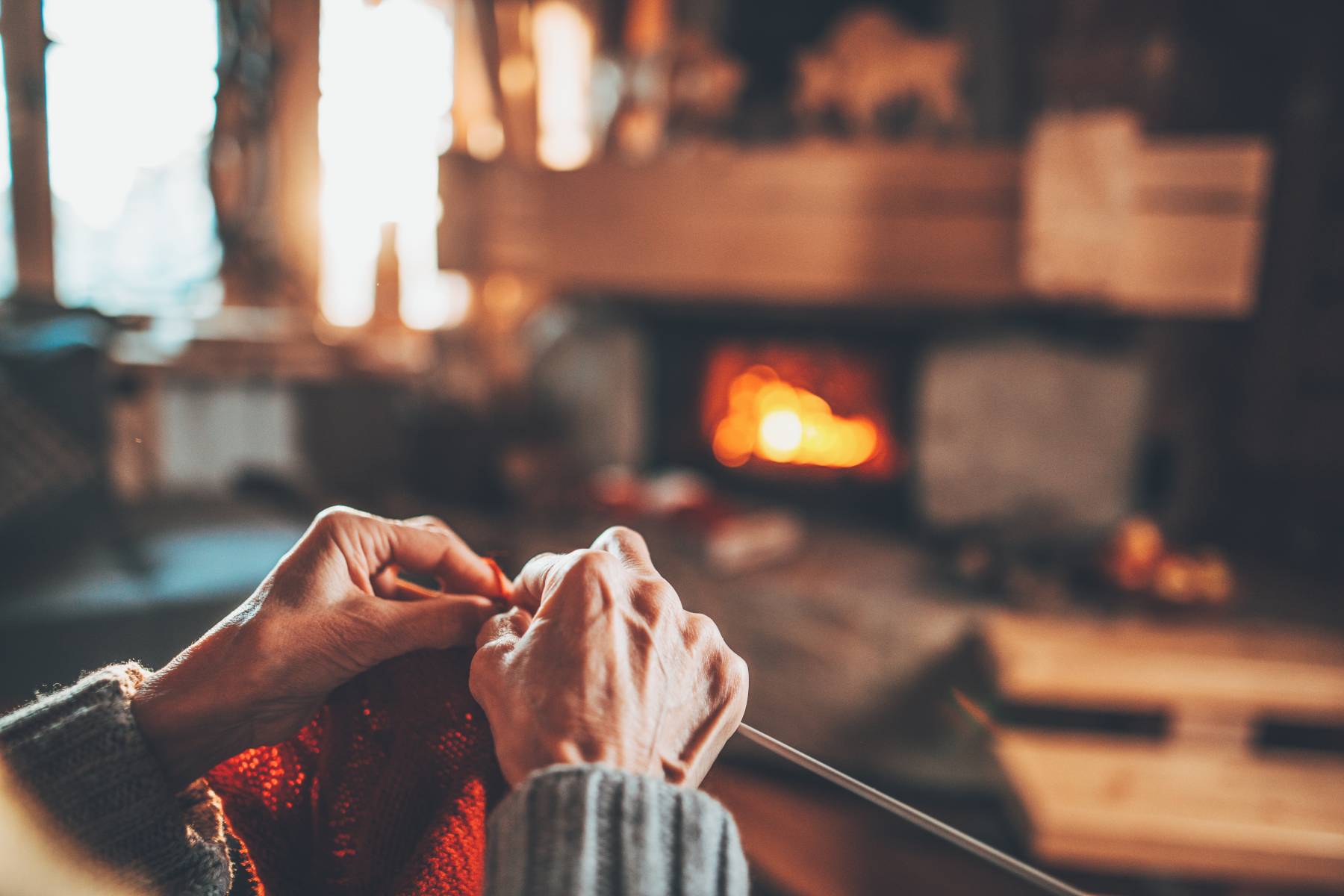 Senior Woman Knitting by a Fire