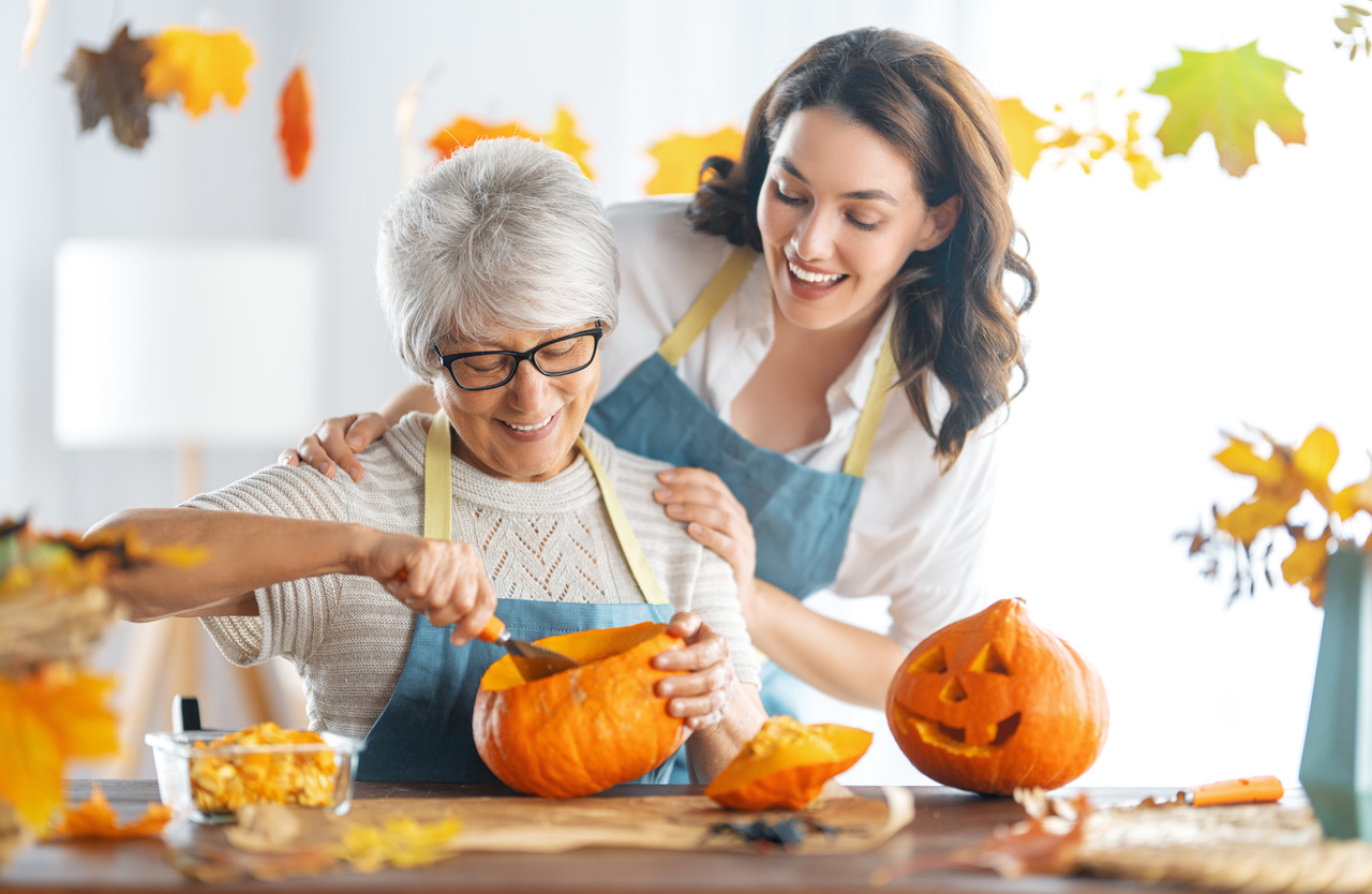 senior woman and cargiver carving pumpkin - Independent Senior Living